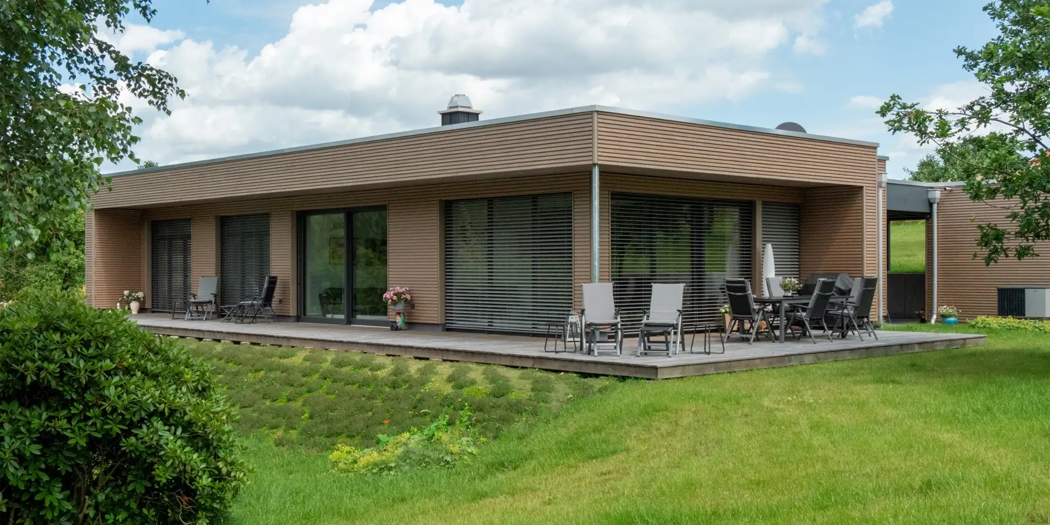 Bungalow mit Holzfassade und großer Terrasse im Garten, Holzhaus vom Architekten