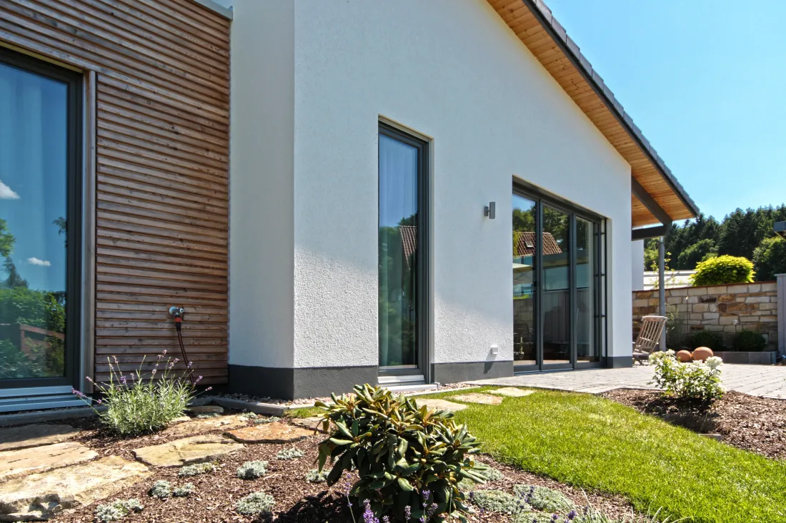 Weißes Architektenhaus mit Holzfassade und Garten