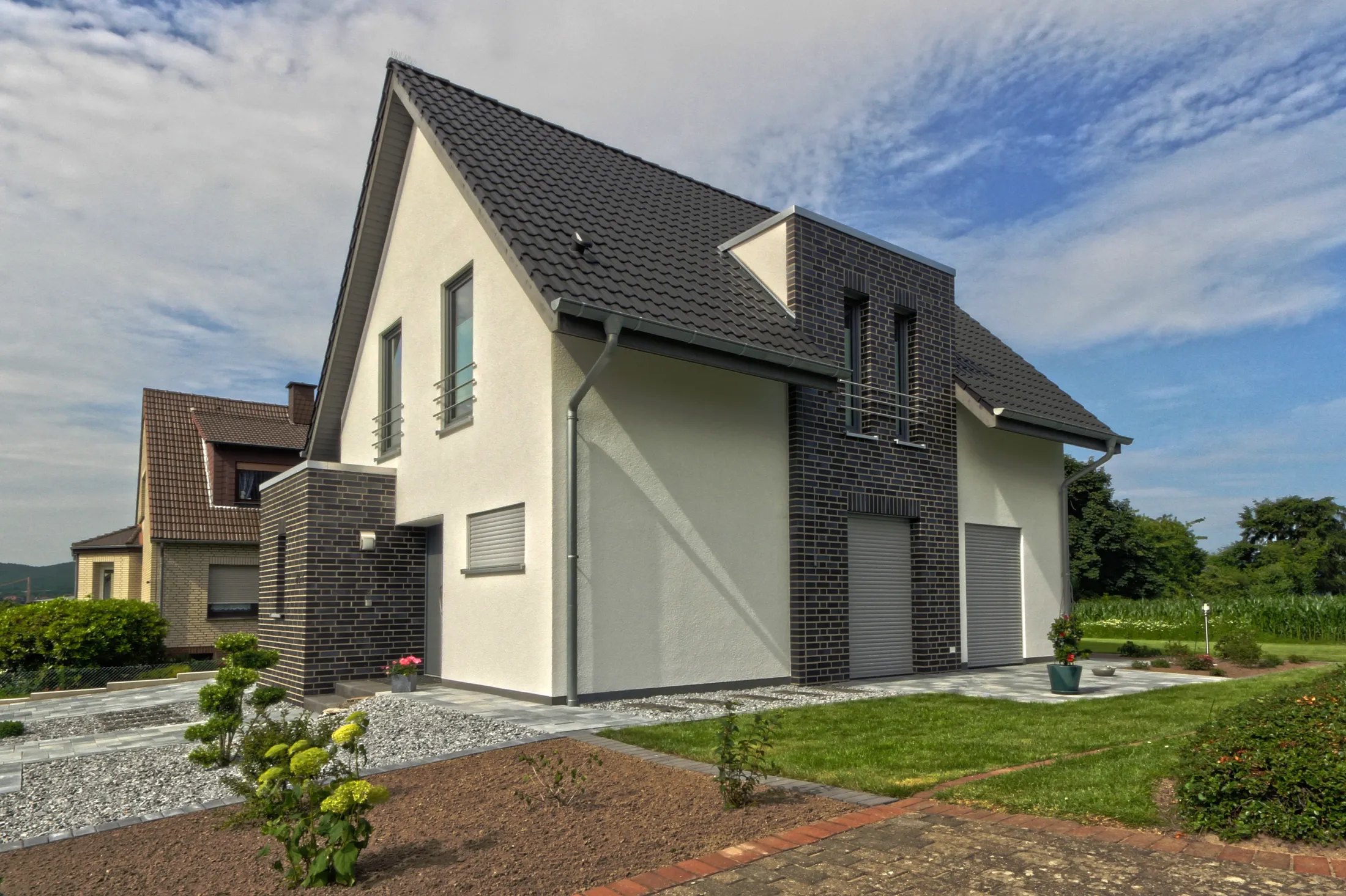 Weißes Haus mit dunklem Klinker und Garten, schlüsselfertig gebaut