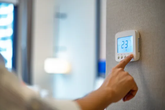 Hand am digitalen Raumthermostat