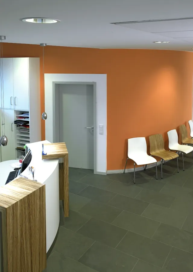 Empfangsbereich einer Praxis mit orangener Wand