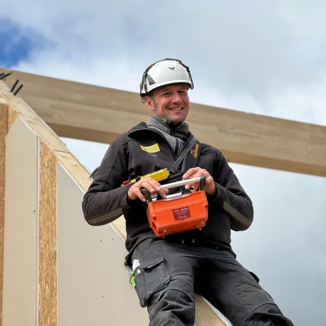 Zimmerer mit Schutzhelm an einer Holzkonstruktion