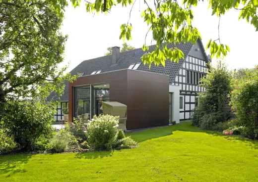 Anbau: Anbau mit dunkler Fassade an ein Fachwerkhaus im Garten