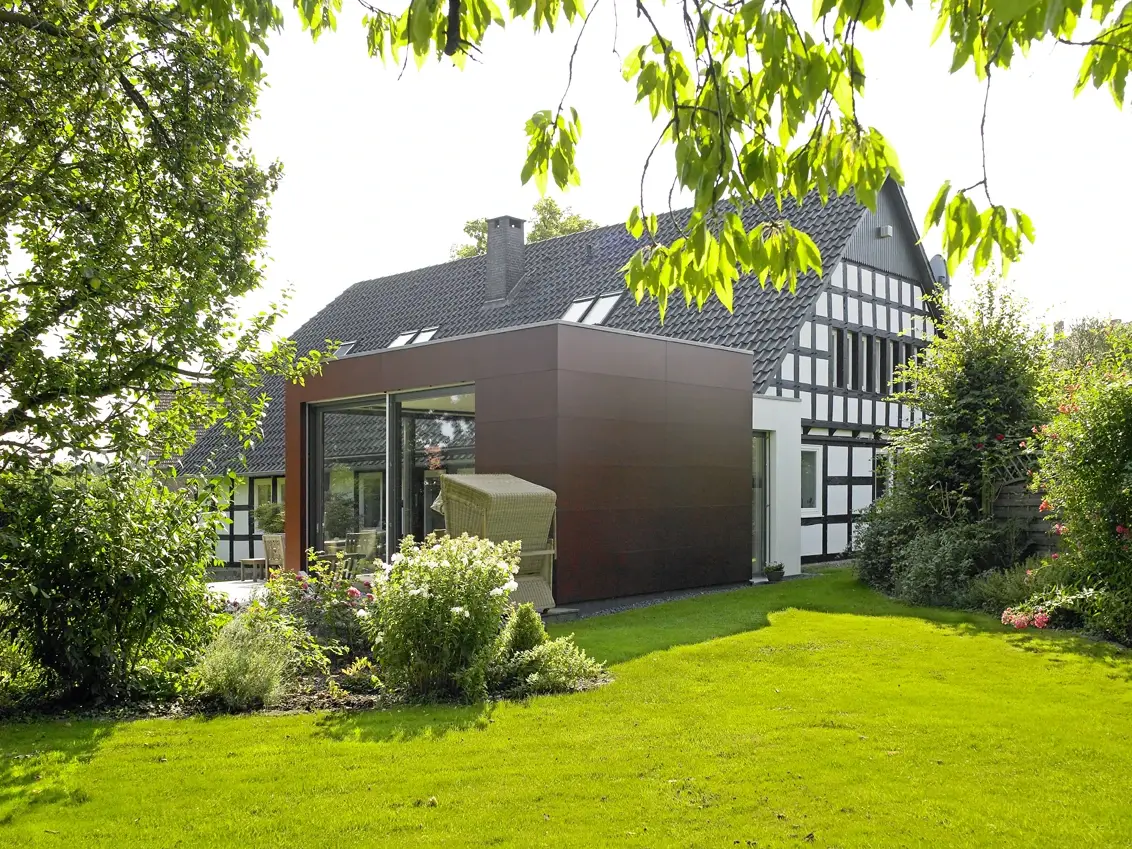 Anbau: Anbau mit dunkler Fassade an ein Fachwerkhaus im Garten
