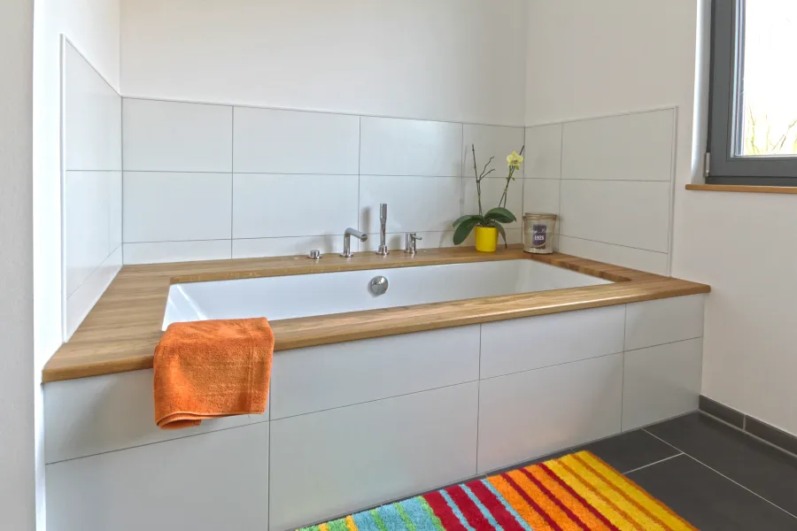 Garagenanbau mit Aufstockung in Bad Oeynhausen: Badewanne mit Holzablage im hellen Bad