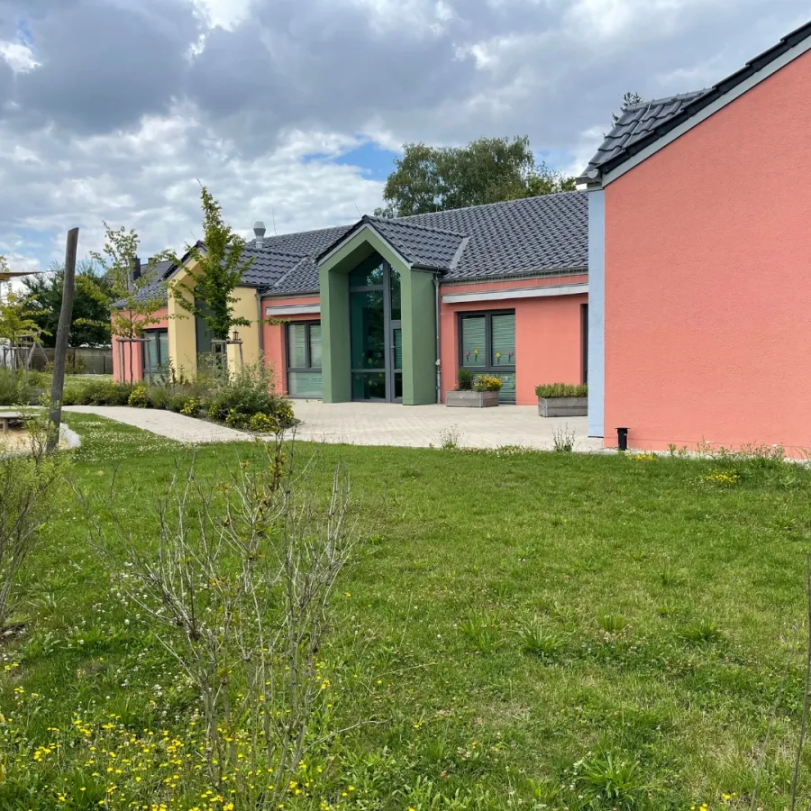 Kita in Holzrahmenbauweise in Herford: Kita mit rosa Fassade und Garten
