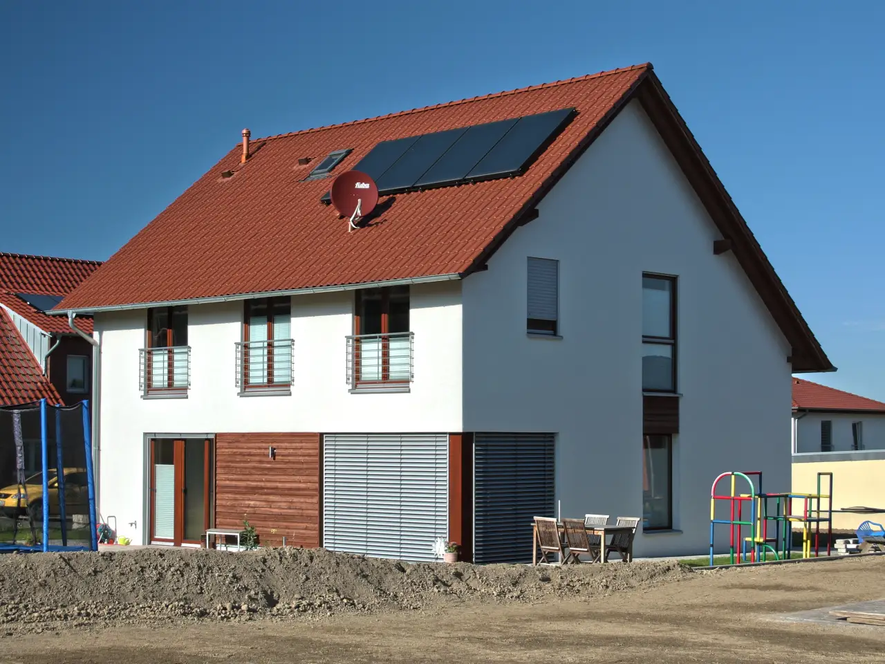 Einfamilienhaus in Bad Oeynhausen: Satteldachhaus mit roten Ziegeln, Solarkollektoren und Holzverkleidung im Erdgeschoss