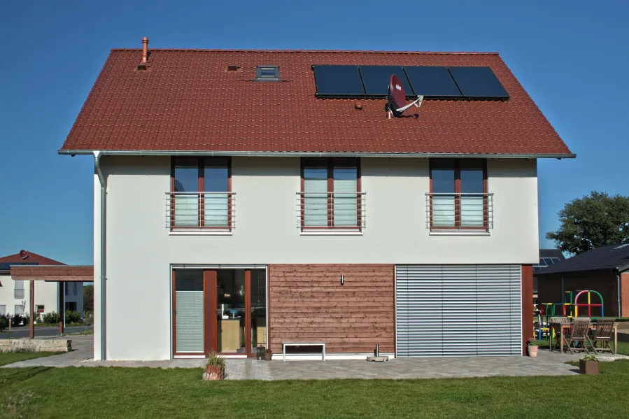 Einfamilienhaus in Bad Oeynhausen: Hausfront mit Solarkollektoren und holzverkleidetem Erdgeschoss