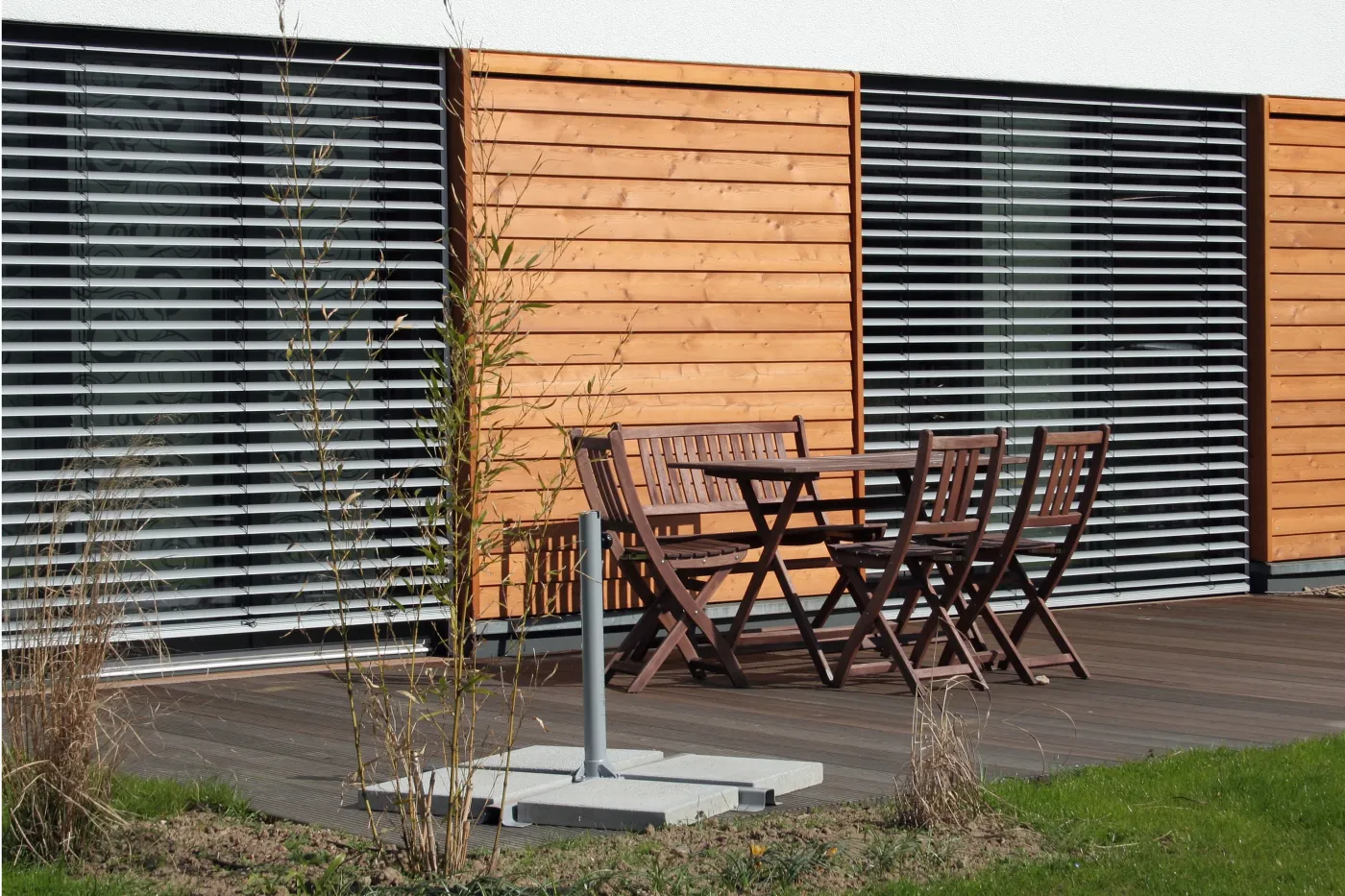 Einfamilienhaus in Bad Oeynhausen: Terrasse mit Gartenmöbeln vor Holzfassade und Raffstore