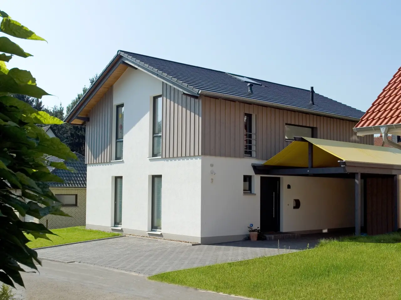 Einfamilienhaus in Bad Oeynhausen: Wohnhaus mit Holzverschalung im Giebel und Carport