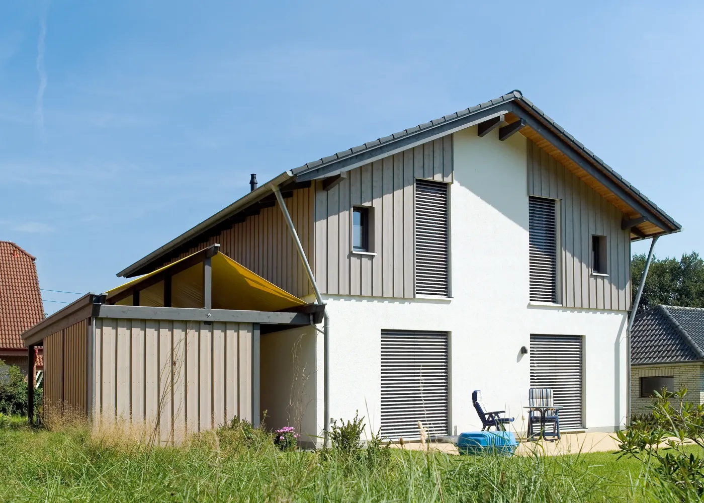 Einfamilienhaus in Bad Oeynhausen: Wohnhaus mit grauer Holzverschalung und Sonnensegel