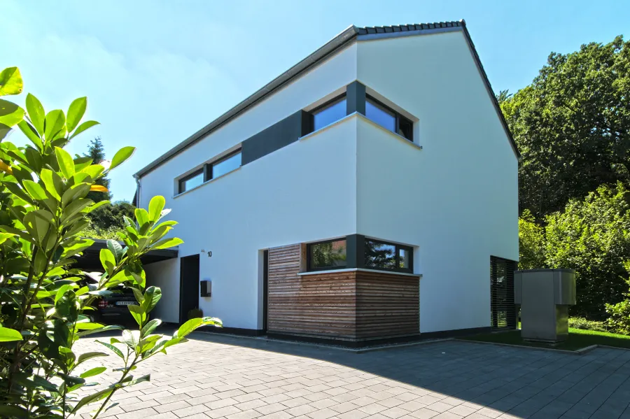 Einfamilienhaus in Bad Oeynhausen: Weißes Wohnhaus mit Holzverkleidung an der Garage
