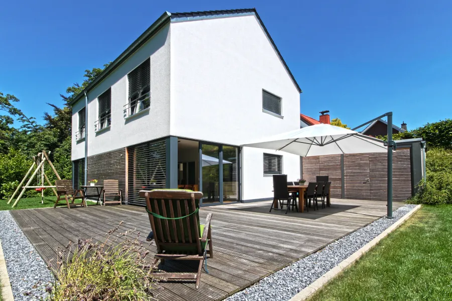 Einfamilienhaus in Bad Oeynhausen: Holzterrasse mit Sonnenschirm am Wohnhaus