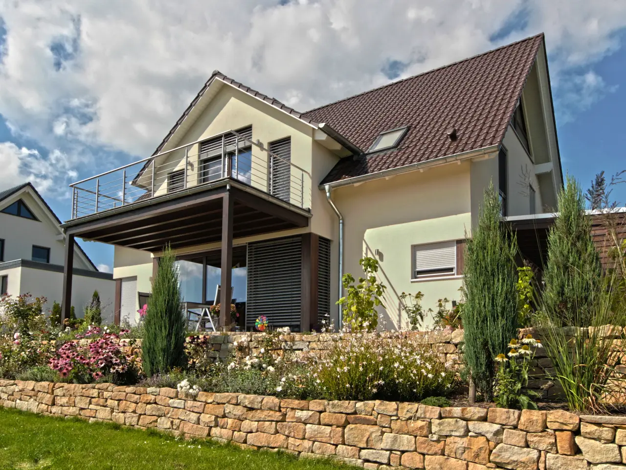 Einfamilienhaus in Hüllhorst: Wohnhaus mit Balkon und Natursteinmauer im Garten