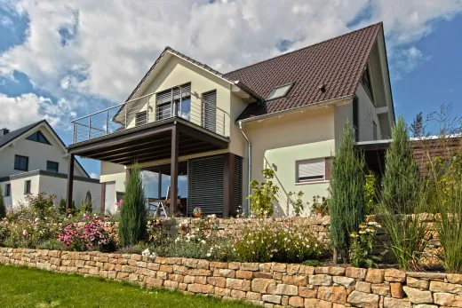 Einfamilienhaus in Hüllhorst: Wohnhaus mit Balkon und Natursteinmauer im Garten
