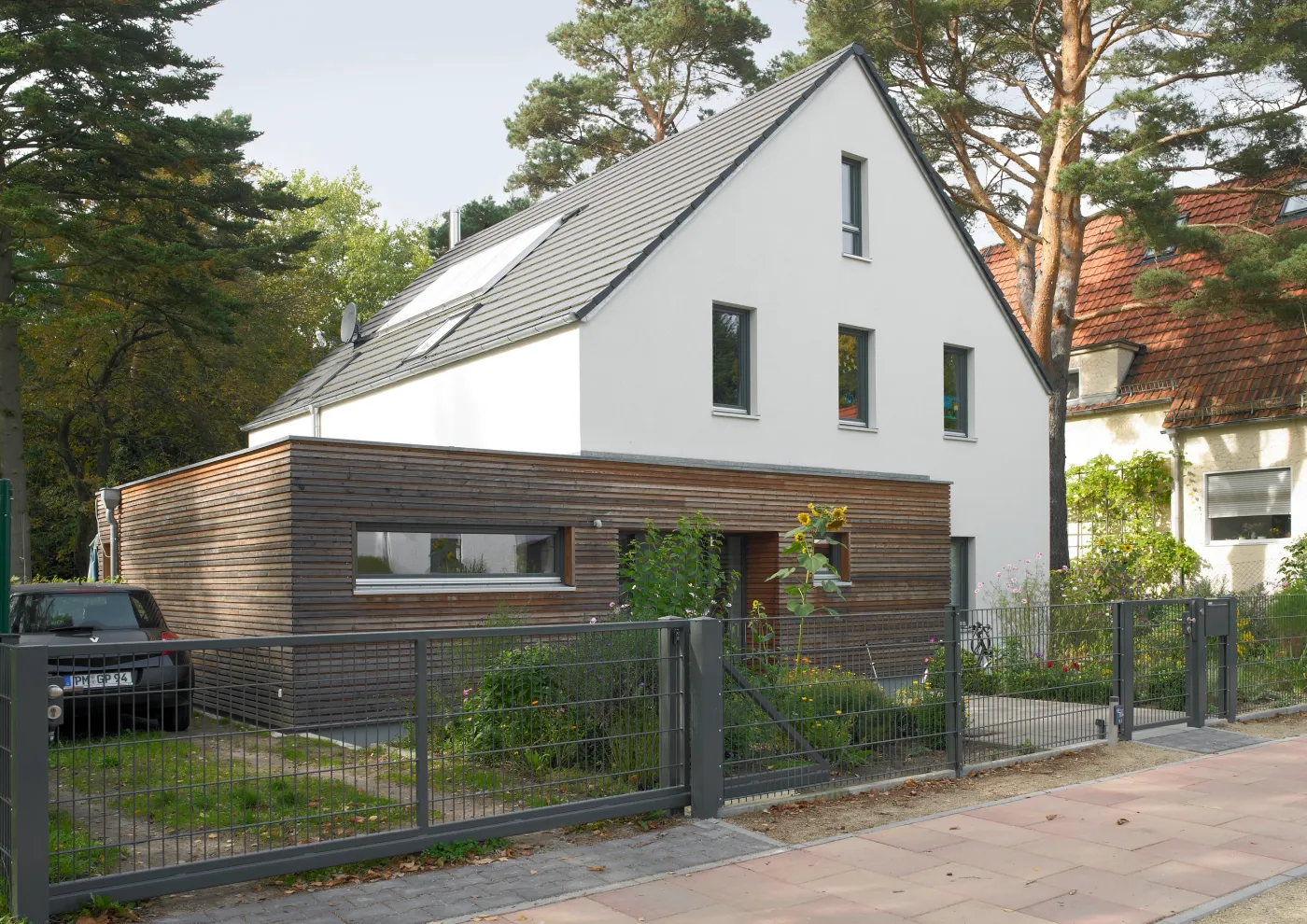 Einfamilienhaus in Kleinmachnow: Satteldachhaus mit Holzanbau hinter dem Zaun