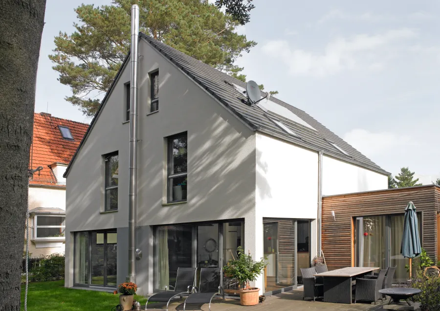 Einfamilienhaus in Kleinmachnow: Wohnhaus mit grauer Fassade und Holzanbau