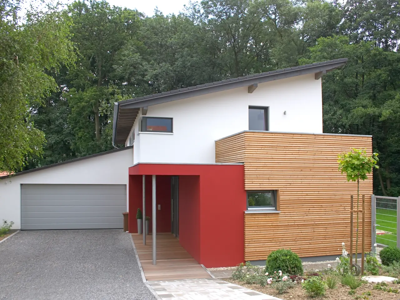 Einfamilienhaus in Löhne: Wohnhaus mit Pultdach, Holzkubus und rotem Eingang
