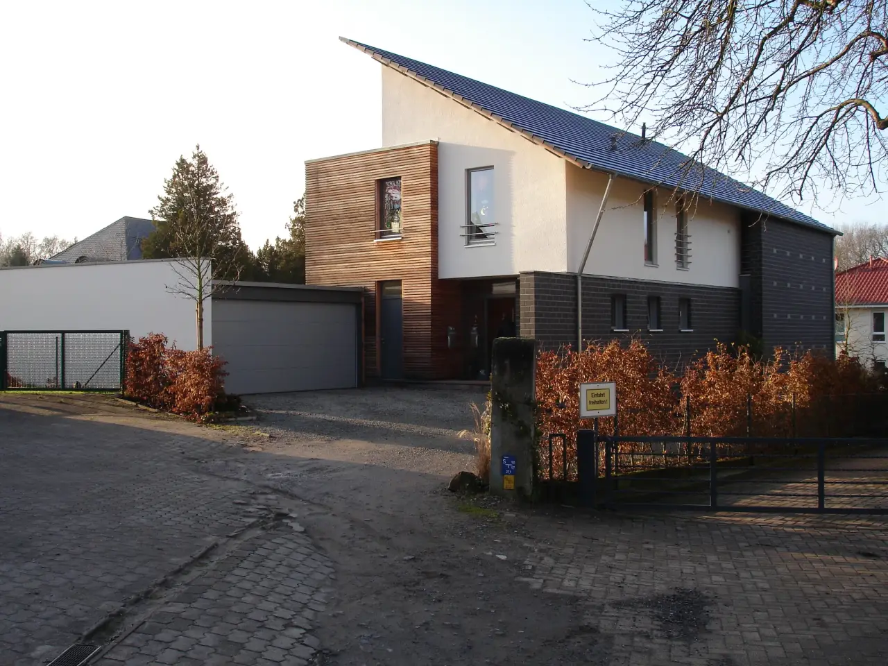 Einfamilienhaus mit Einliegerwohnung in Bad Oeynhausen: Wohnhaus mit Pultdach und Holzfassade am Abend