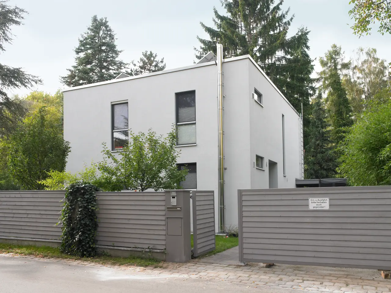 Einfamilienhaus in Berlin-Spandau: Kubisches Wohnhaus hinter grauem Holzzaun