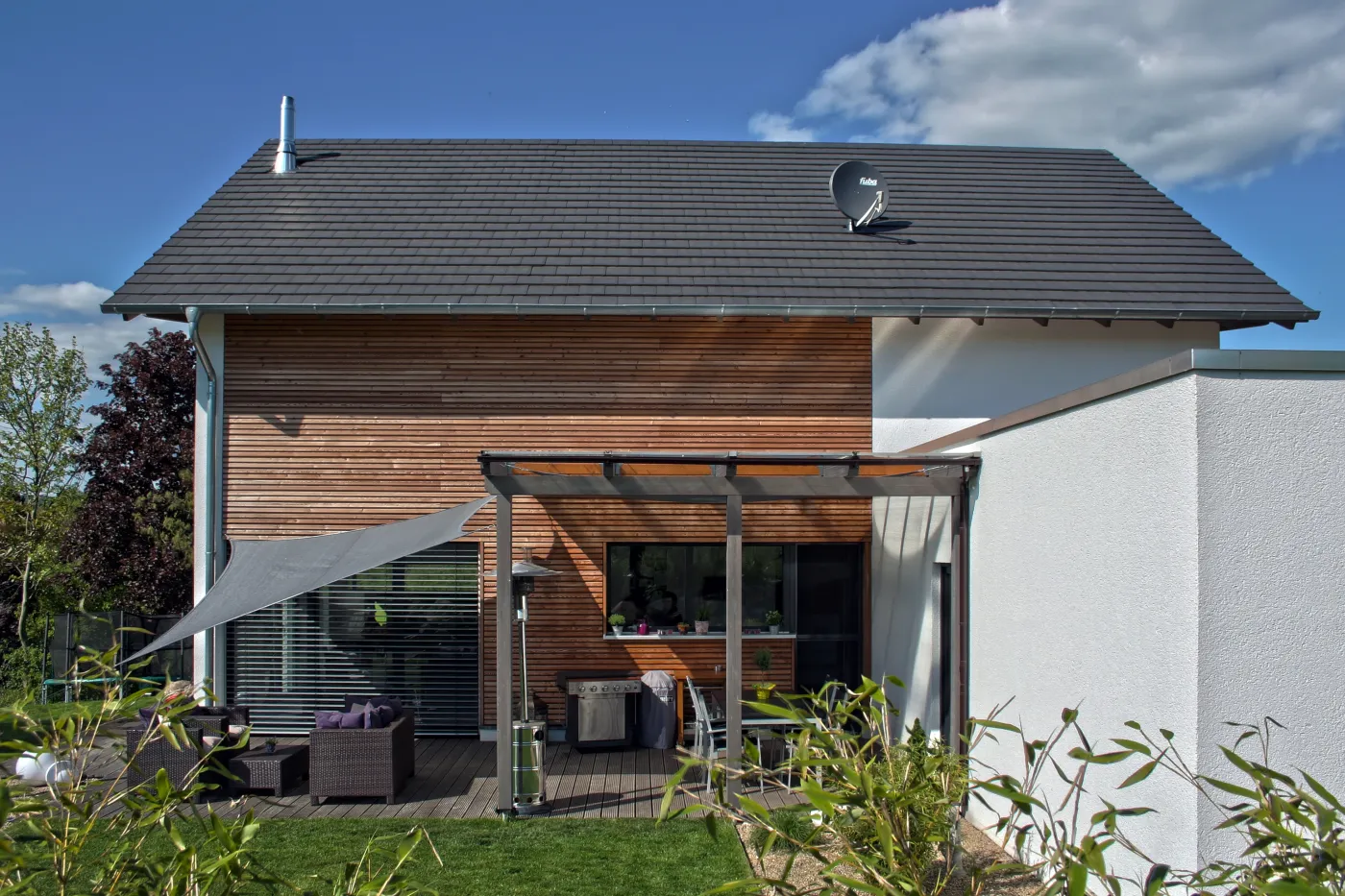 Einfamilienhaus in Porta Westfalica: Terrasse mit Sonnensegel vor der Holzfassade