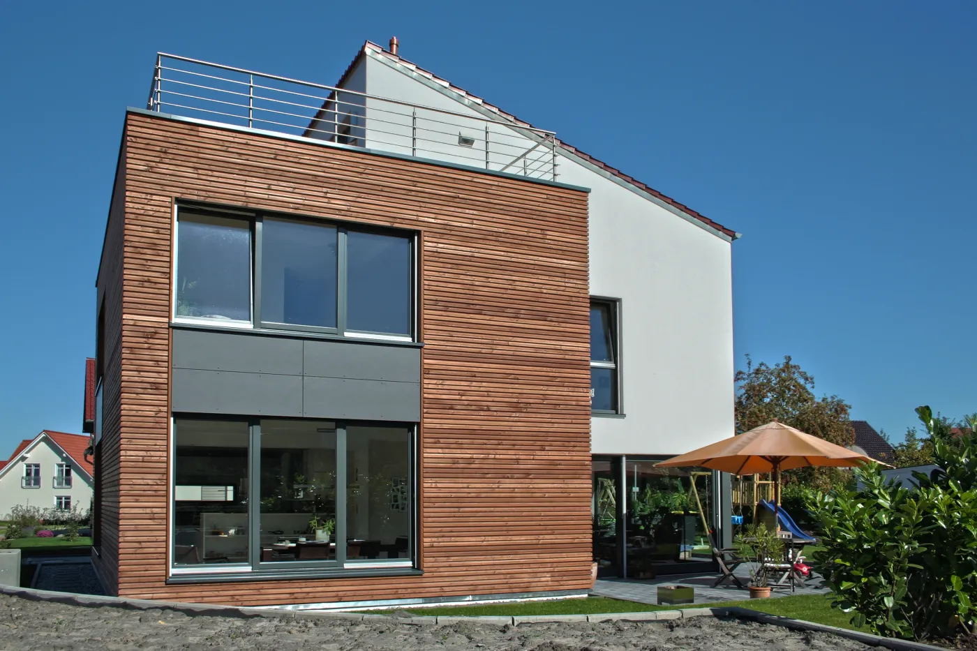 Einfamilienhaus in Werther: Holzfassade mit Dachterrasse und Sonnenschirm