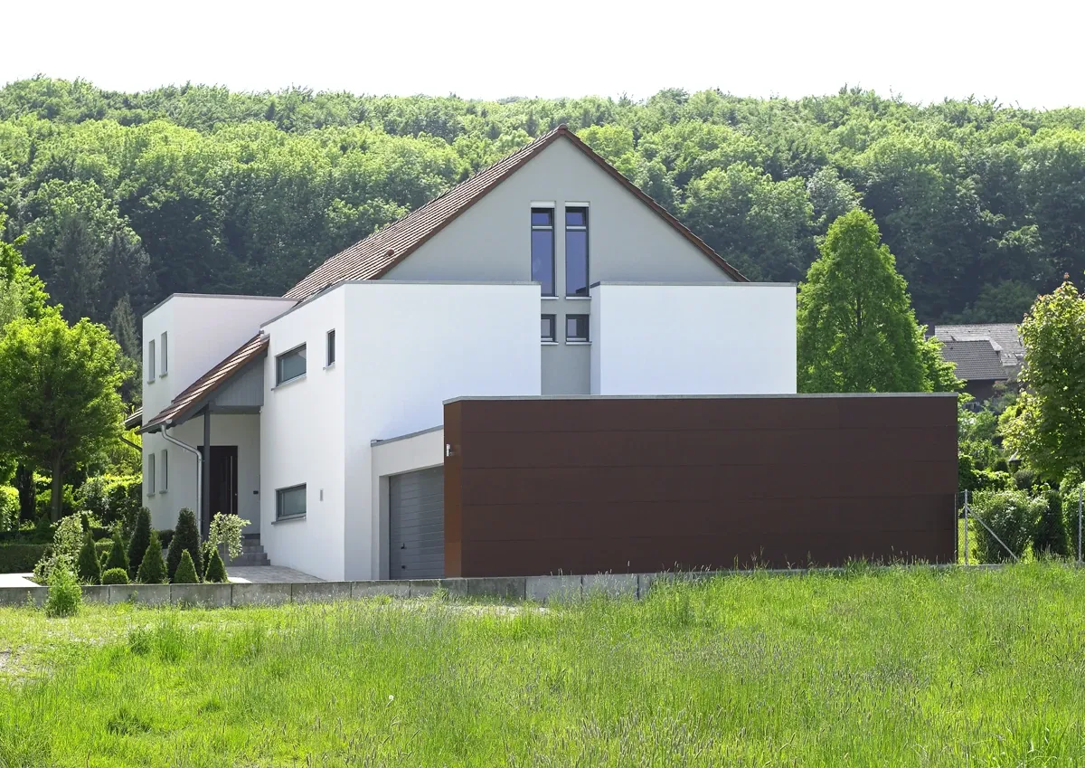 Einfamilienhaus in Howacht: Wohnhaus vor bewaldetem Hang