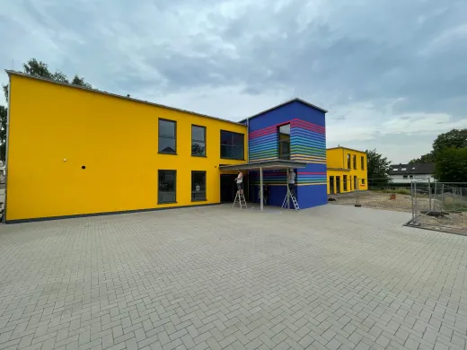 Kita in Westerenger: Kita mit gelber Fassade und bunt gestreiftem Bau