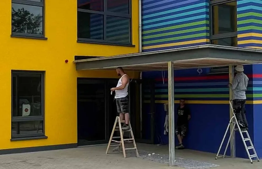 Kita in Westerenger: Handwerker bei Arbeiten an der bunten Kita-Fassade