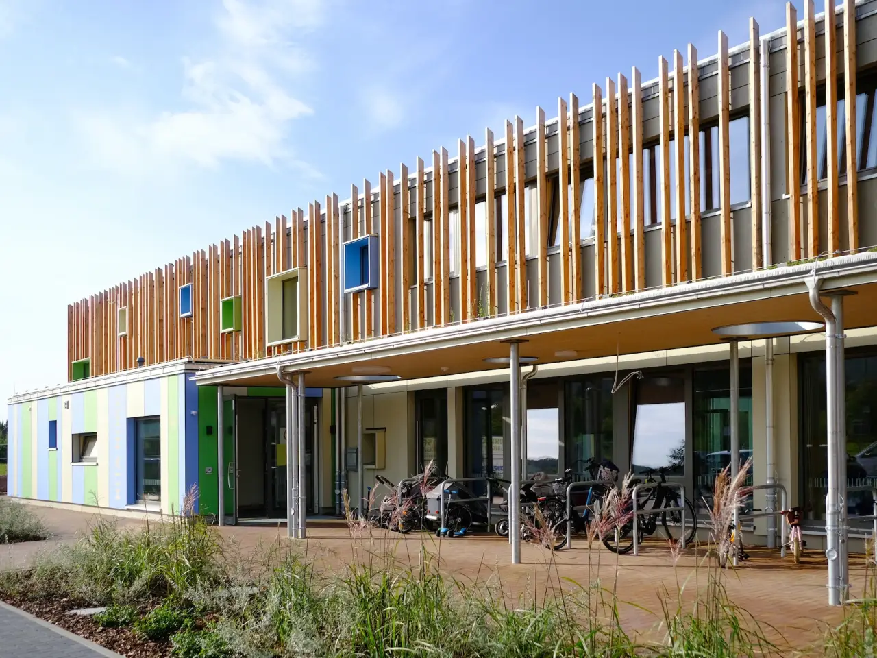 Kita-Neubau in Hameln: Kita mit vertikaler Holzlamellenfassade und farbigen Fensterrahmen