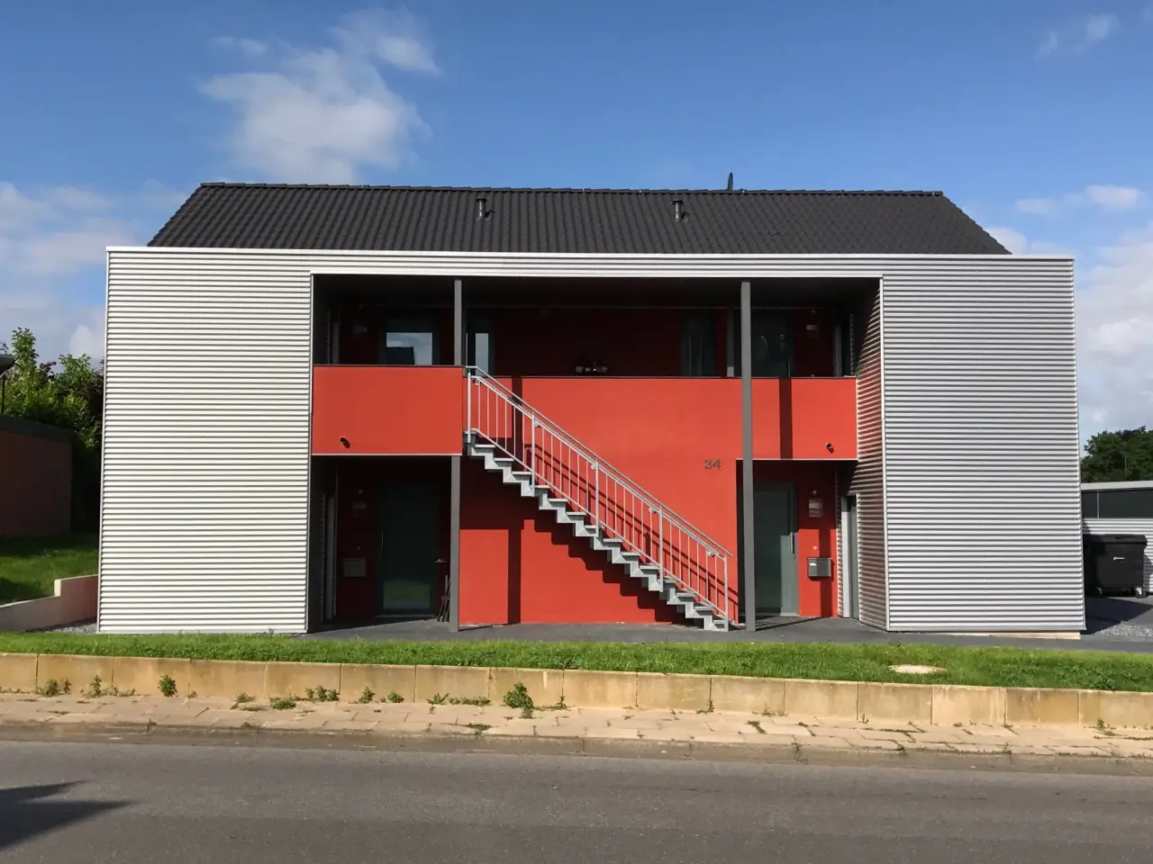 Soziale Wohnanlage in Spenge: Wohnanlage mit Holzfassade und roter Außentreppe