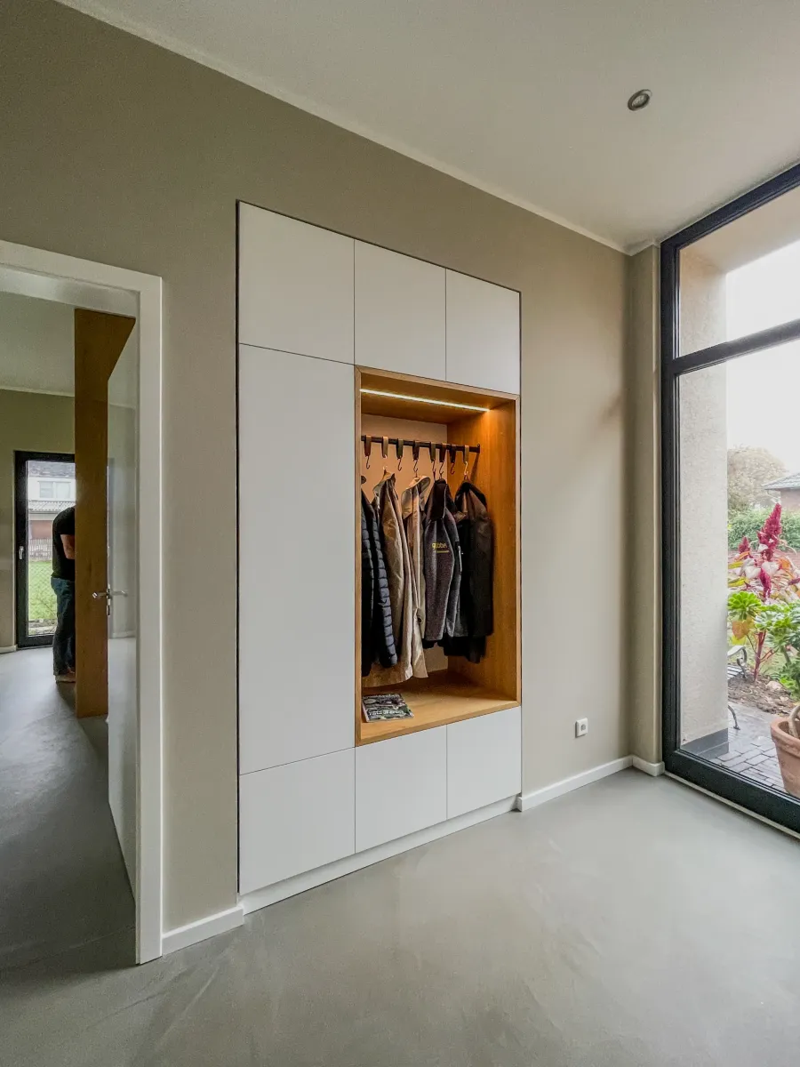 Portrait Zuhause in der Obstwiese: Garderobe mit beleuchteter Holznische im Eingang